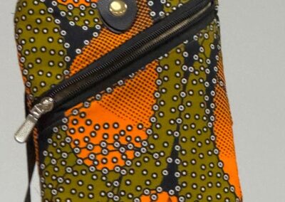 Handmade crossbody bag with orange, olive, and black African print fabric and leather zipper tab