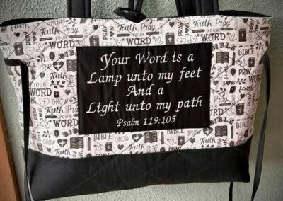 Black and white quilted tote bag with faith-themed print and embroidered Psalm 119:105 verse patch