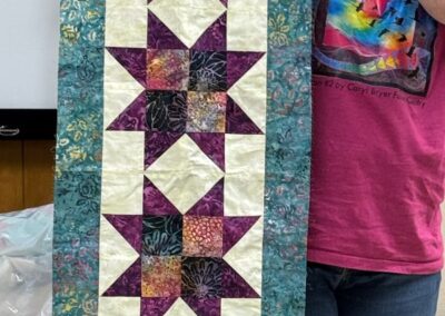 Woman holding a handmade purple and teal star-pattern quilted table runner
